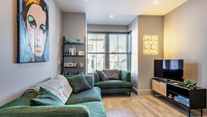 A modern living room with a green sofa, a television, and a bookshelf. - 3 Bed in Fowey (oc-p29280) (Fowey)