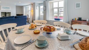 Een eetgedeelte met een ontbijttafel, inclusief gebak en een taart, in een moderne kamer met uitzicht.
