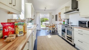 A modern kitchen with white cabinets, stainless steel appliances, and a dining area with a view of the garden.