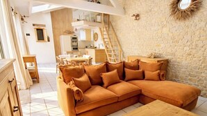 A modern living room with a sectional sofa, wooden coffee table, and a stone wall. - Charming house with pool, 10 min from La Rochelle (Dompierre-sur-Mer)