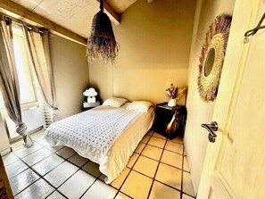 A bedroom with a bed, a nightstand, a mirror, and a door. - Charming house with pool, 10 min from La Rochelle (Dompierre-sur-Mer)