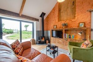 Un salón acogedor con chimenea, un sillón verde, un sofá de cuero y un televisor.
