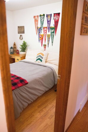 A bedroom with a bed, pillows, a bedside table with a lantern, and a wall decorated with colorful pennant banners. - 4-bedroom house in peaceful Harrison with cool AC breeze (Harrison)