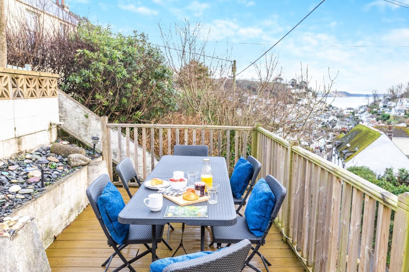 Eine Terrasse mit einem Frühstückstisch, umgeben von Stühlen und mit Blick auf eine schöne Landschaft.