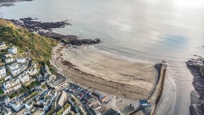 An aerial view of a coastal town with a sandy beach, rocky shoreline, and residential buildings. - 3 Bed in Looe (oc-s29266) (Looe)