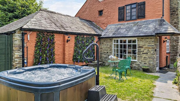Un jacuzzi en un jardín con un edificio de piedra al fondo.