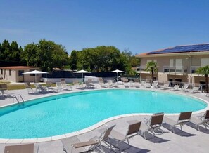 A swimming pool with lounge chairs and umbrellas, surrounded by buildings and trees. - Le Gemme Luxury (Marina di Zambrone)