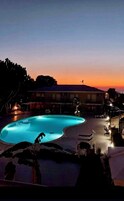Una piscina al anochecer con un edificio al fondo.