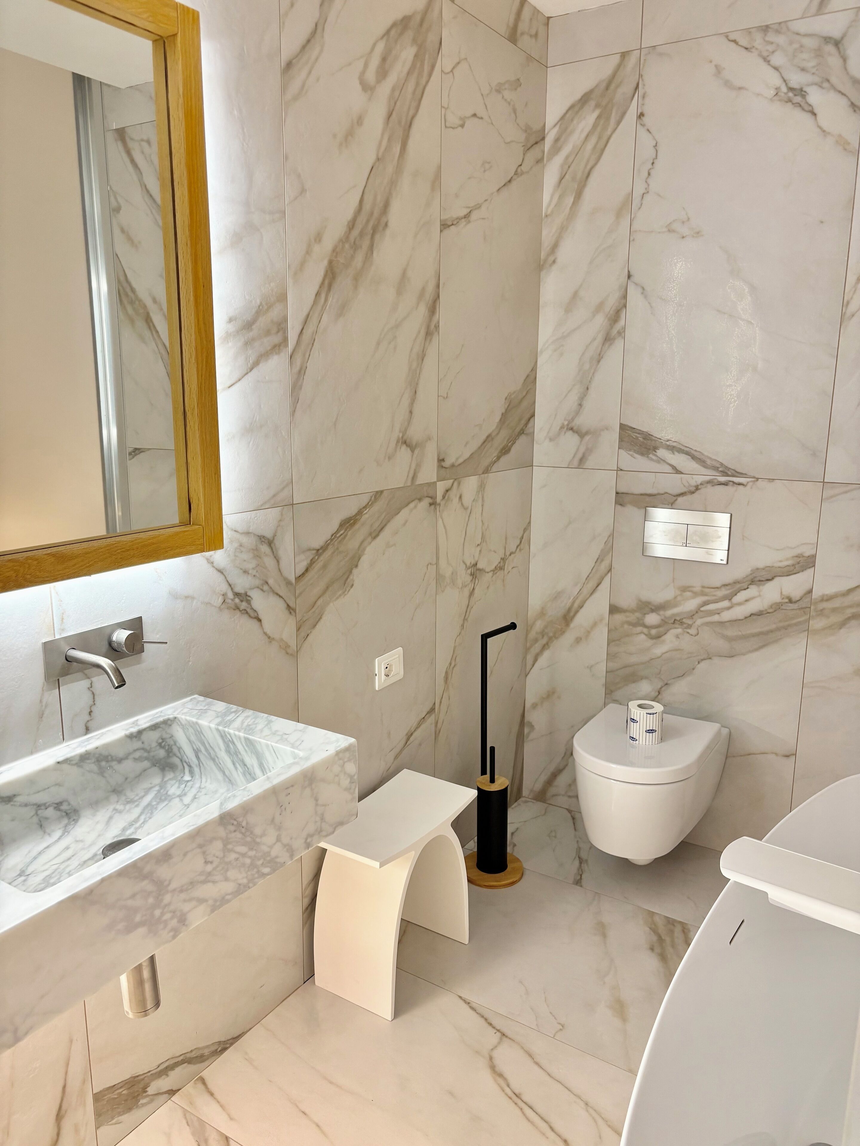 A modern bathroom with a marble sink, a toilet, and a bidet.