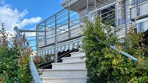 Un conjunt d'escales de formigó que condueixen a un edifici, amb barana metàl·lica i vidriera.