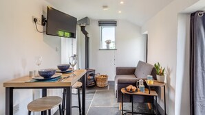 Un espace de vie compact comprenant un coin cuisine, un coin repas, un canapé et un téléviseur fixé au mur.