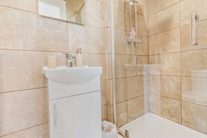 A modern bathroom with a glass-enclosed shower, a white sink, and beige tiles. - 1 Bed in Llanteg (oc-b29484) (Llanteg)