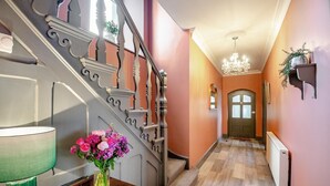 Eine Treppe mit aufwendiger Geländer, die zu einer Tür führt, ein Blumenstrauß auf einem Tisch und ein Chandelier im Flur.