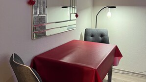 A dining area with a red table, two chairs, a mirror with a brick pattern, and a wall-mounted light fixture. - A central, cozy family retreat for 4 people—perfect for short getaways (Bremerhaven)