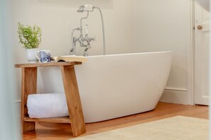 A modern bathroom with a freestanding bathtub, a wooden stool, and a potted plant. - 4 Bed in Polruan (oc-n29511) (Fowey)