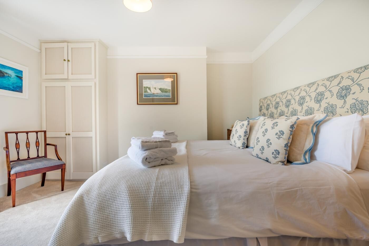 A bedroom with a bed, a chair, a framed picture, and a door.