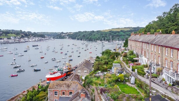 A harbor with boats, a red ship, and a building with a garden.