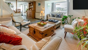 A spacious living room with a large window, a wooden coffee table, and a comfortable seating area.