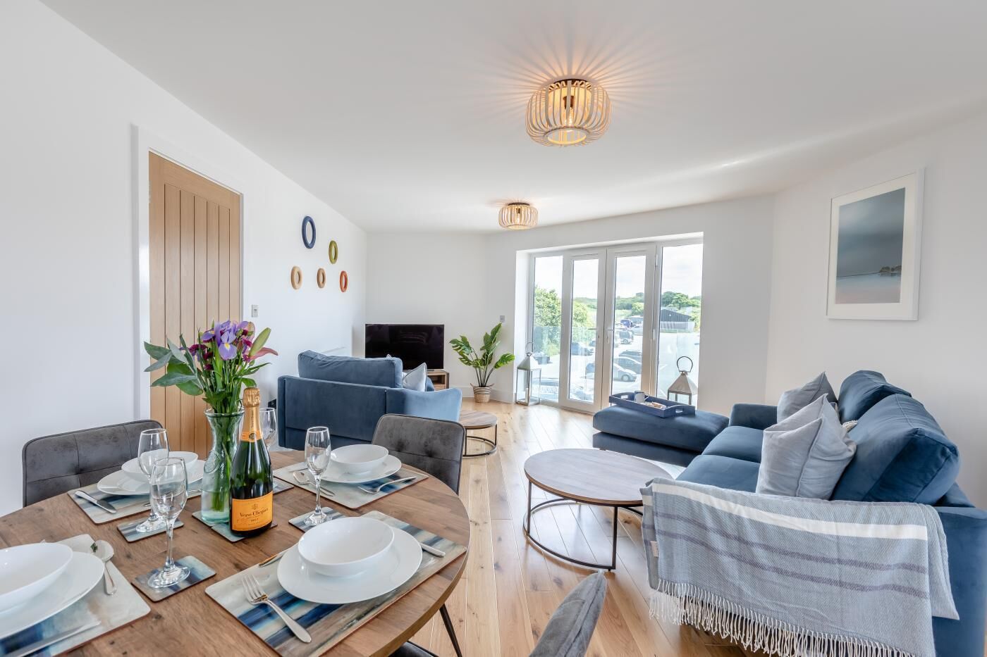 A modern living room with a dining area, a sofa set, and a TV.