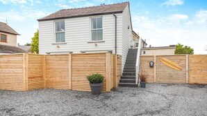 Une maison à deux étages, avec une clôture en bois, une allée en gravier et un petit jardin.