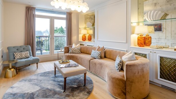 A living room with a sofa, armchair, and coffee table, a chandelier, and a view of the outdoors. - 6 Bed in Abersoch (oc-c29569) (Abersoch)
