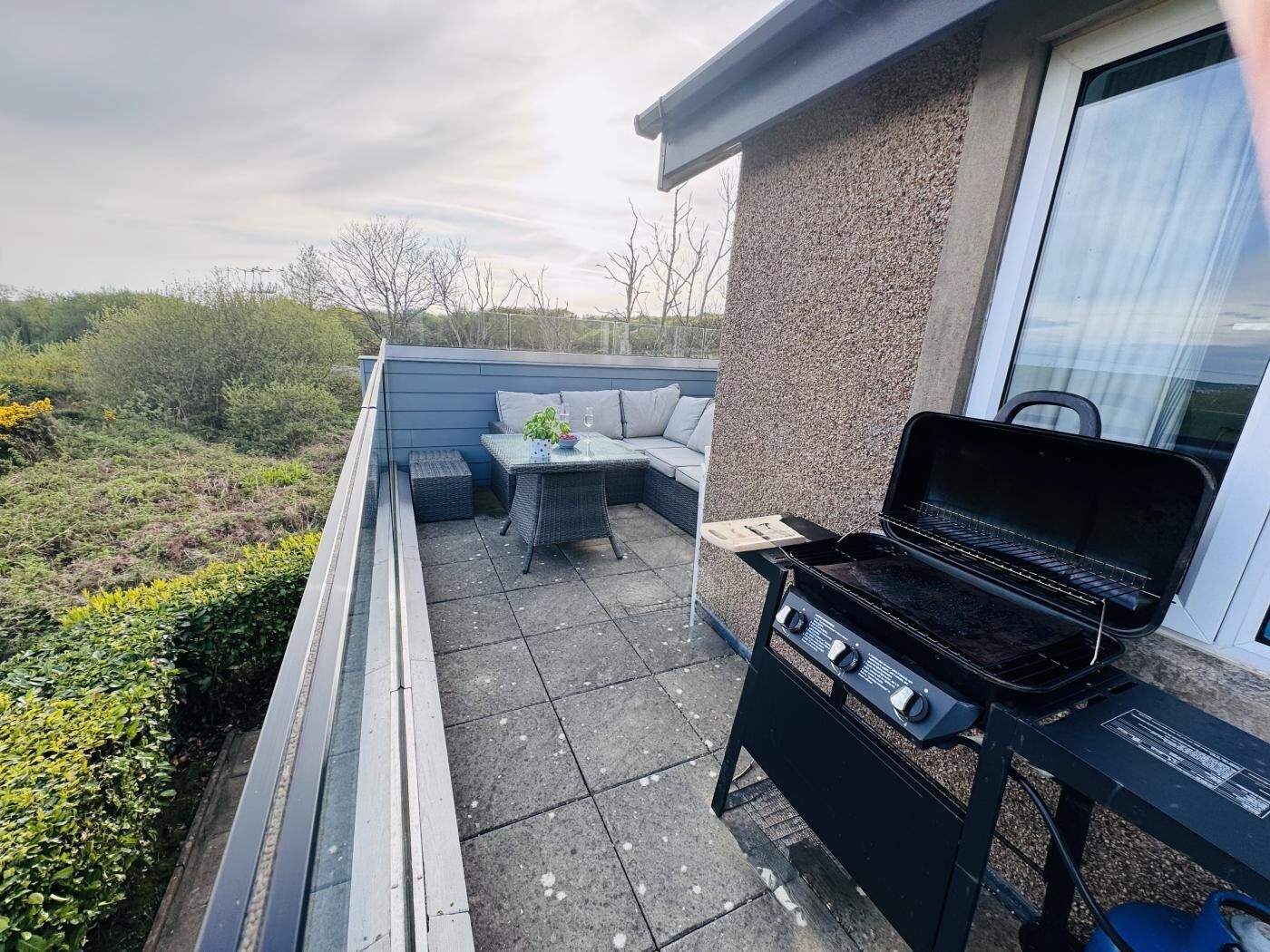 An outdoor patio with a grill, seating area, and a view of the surrounding landscape.