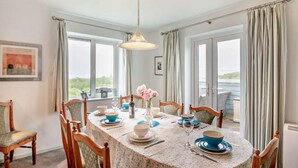 A dining area with a round table set for four, surrounded by wooden chairs. - 3 Bed in Mynytho (oc-m29517) (Mynytho)