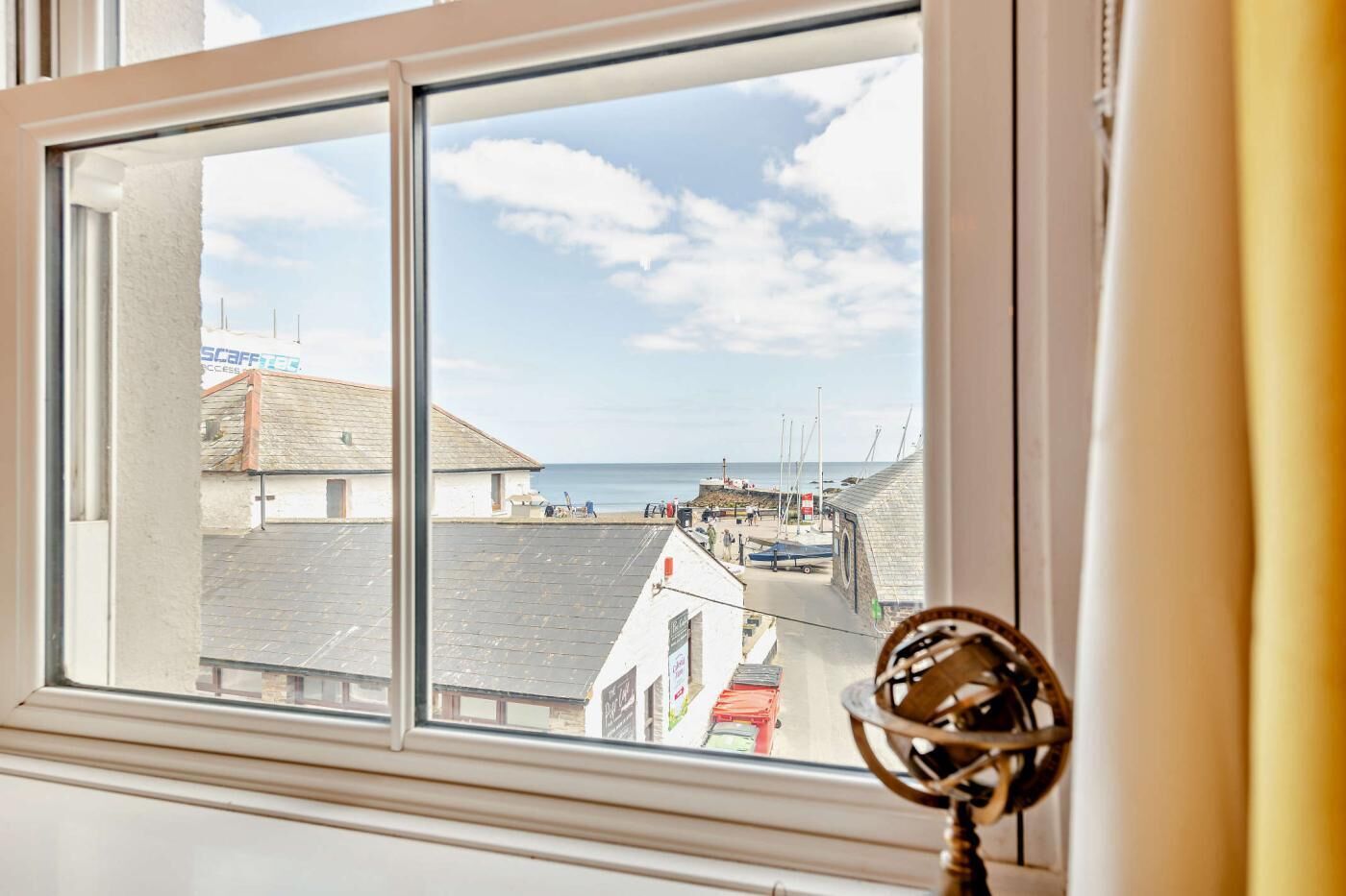 A window with a view of a coastal town, including buildings and a pier.