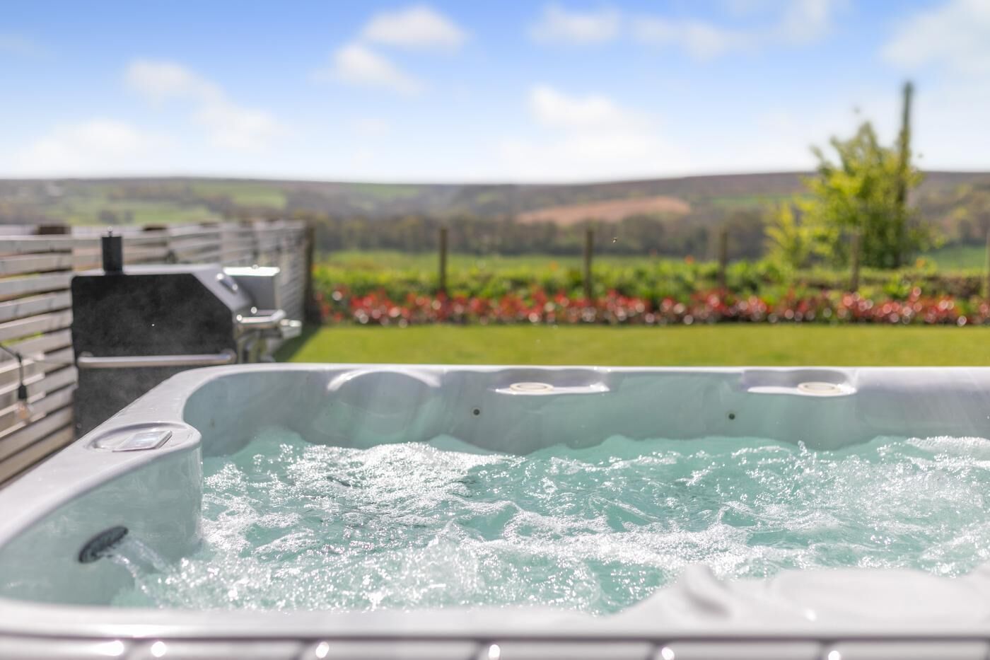 Una vasca idromassaggio con vista su un giardino curato e dolci colline in lontananza.