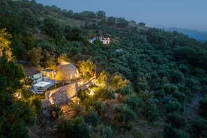 A large, dome-shaped building surrounded by lush greenery, with a stone pathway leading to a pool area. - Gogna Luxury Domes in Crete, Greece (Crete)