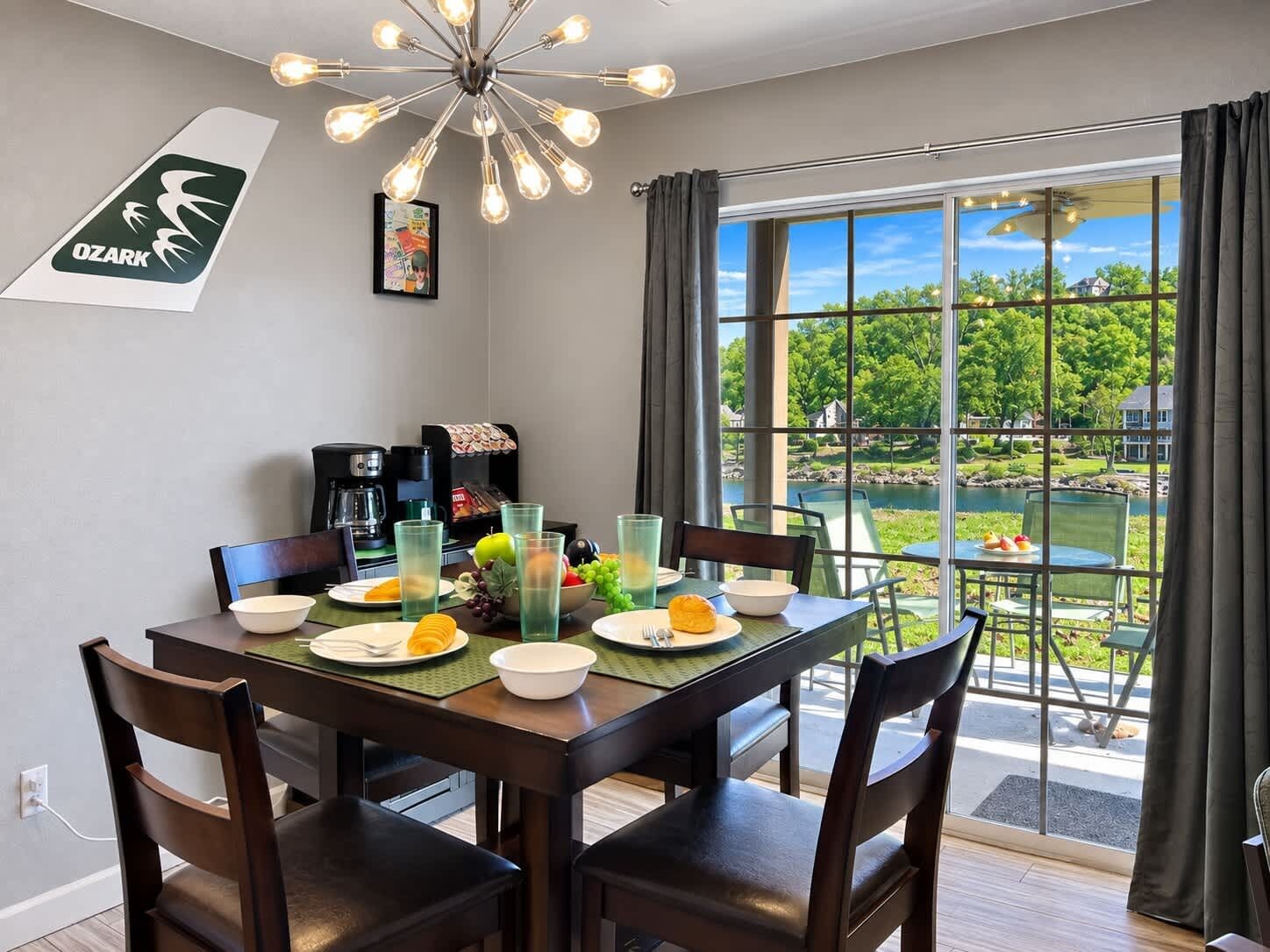 A dining area with a table set for four, a coffee machine, and a view of a lake.