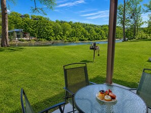 A glass table with a plate of pastries, a chair, and a view of a river and forest. - 692 Walk-in Lakefront Oasis - Cozy, Calm, Scenic (Branson)