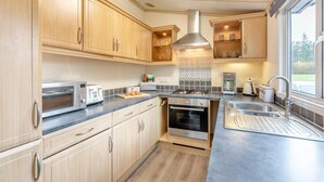 A modern kitchen with wooden cabinets, a built-in oven, a gas stove, and a stainless steel sink.
