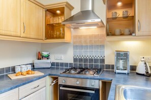 A kitchen with a gas stove, oven, and a coffee machine.