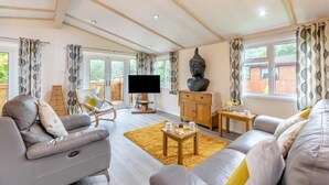 A spacious living room with a sofa set, a wooden cabinet, a television, and a Buddha statue.