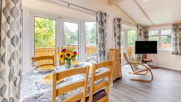 A dining area with a table set for two, a television, and a wooden chair.