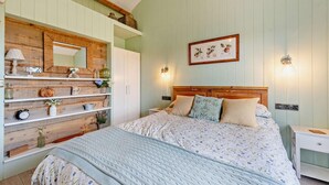 A bedroom with a bed, wooden shelves, a wardrobe, a mirror, and wall-mounted lights. - 1 Bed in Dre-Fach Felindre (oc-a29876) (Felindre)
