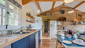 A rustic kitchen with wooden beams, a large window, and a dining area with a table set for two. - 1 Bed in Dre-Fach Felindre (oc-a29876) (Felindre)