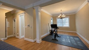 A spacious room with hardwood floors, a black exercise mat, and a stationary bike. - Near Downtown and Midtown, Quiet Cul-de-sac Decatur Home with Deck & Balcony, (Decatur)