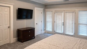 A bedroom with a bed, a dresser, a TV, and a closet with sliding doors. - Near Downtown and Midtown, Quiet Cul-de-sac Decatur Home with Deck & Balcony, (Decatur)