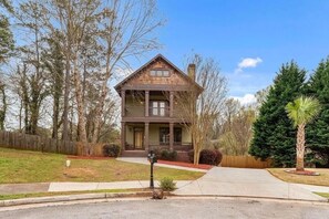 A two-story house with a front porch, surrounded by trees and a well-maintained lawn. - Near Downtown and Midtown, Quiet Cul-de-sac Decatur Home with Deck & Balcony, (Decatur)