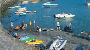 Un port où des bateaux sont amarrés et où l’on peut voir des gens près de l’eau.