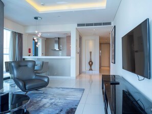 A modern living room with a flat-screen TV, a leather chair, a glass coffee table, and a patterned rug. - Luxury 2BR at Paramount Tower - Business Bay - Pool & Dubai Frame Views (Business Bay)