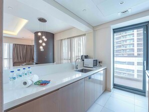 Eine moderne Küche mit einer großen Kochinsel, einer Mikrowelle und einem Spülbecken. Auf der Arbeitsplatte stehen Wasserflaschen und Snacks.
