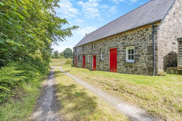 A stone building with red doors and a gravel path leading to it.