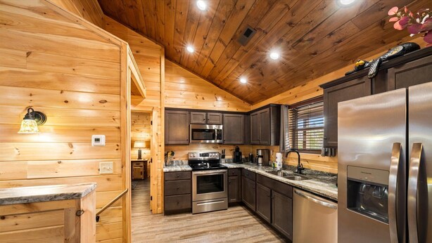 Una cocina moderna con paredes de madera, electrodomésticos de acero inoxidable y piso de madera.