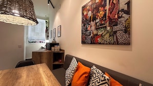 A modern interior with a wooden dining table, a sofa with patterned cushions, and a vibrant market scene painting on the wall. - NEW! Nice apartment 2 steps from villa Borghese and Spanish Steps (Roma)