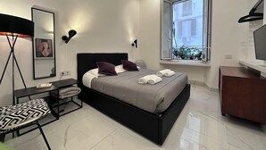 A modern bedroom with a bed, bedside tables, a chair, a desk, a TV, and a window with a view. - NEW! Nice apartment 2 steps from villa Borghese and Spanish Steps (Roma)