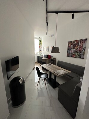 Een moderne keuken met een eethoek, een televisie en een prullenbak.