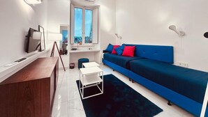 A modern living room with a blue sofa, a small white table, and a dark rug. - NEW! Nice apartment 2 steps from villa Borghese and Spanish Steps (Roma)